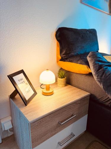 a table with a lamp on a nightstand next to a bed at Apartment Schwarzwaldhöhen Pforzheim-Birkenfeld in Birkenfeld