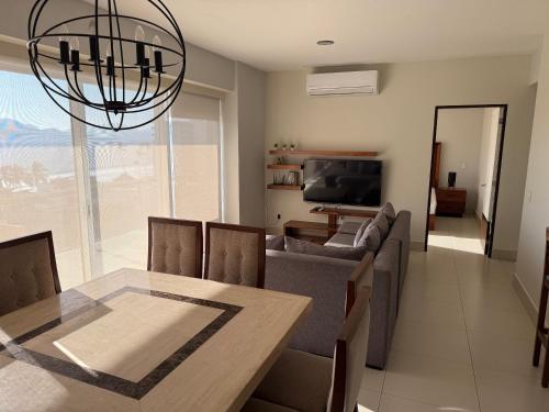 曼萨尼约HERMOSO DEPARTAMENTO DE LUJO EN MANZANILLO A PIE DE PLAYA EN PONTO HORIZONTE MANZANILLO. PARA HASTA 8 PERSONAS, DE LO MEJOR DE MANZANILLO. HERMOSA VISTA AL MAR的客厅配有餐桌和沙发