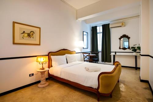 a bedroom with a bed and a table and a lamp at The Character Yaowarat MRT วัดมังกร in Bangkok