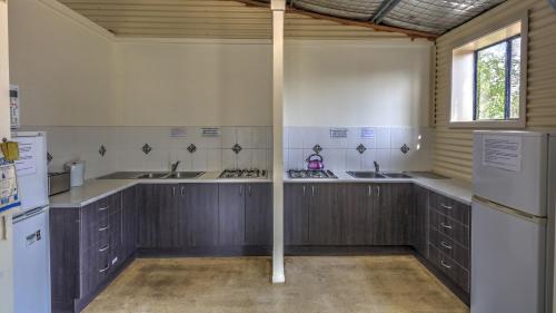 a kitchen with three sinks and a refrigerator at Tiny Away Escape at Granite Belt - Sommerville Valley in Stanthorpe