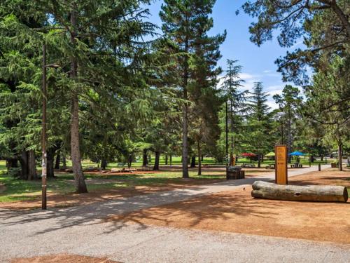 a log on the ground in a park with trees at Chic 1-Bed Apartment Near Canberras Bustling CBD in Turner