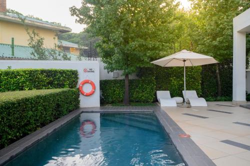 a swimming pool with an umbrella and two chairs at The Capital on Bath in Johannesburg