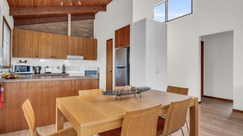 a kitchen and dining room with a wooden table and chairs at Coolabah Court in Merimbula