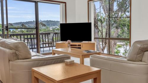 a living room with two chairs and a television at Coolabah Court in Merimbula