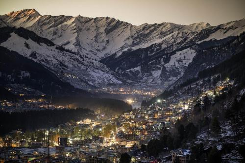 a view of a city with snow covered mountains at Echor Himalayan Heights Luxe Manali in Manāli