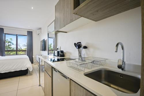 a kitchen with a sink and a bed in a room at The Capital on Bath in Johannesburg