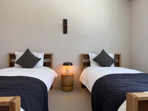 two beds in a room with a lamp on a table at soil Hakuba in Hakuba