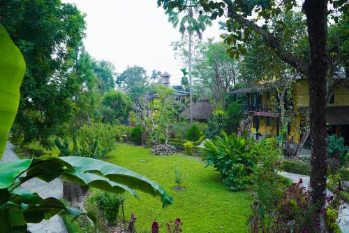 a garden with flowers and plants in front of a house at Sapana Village Lodge in Sauraha