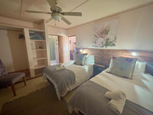 a hotel room with two beds and a fan at Kliprand Guest House in Springbok