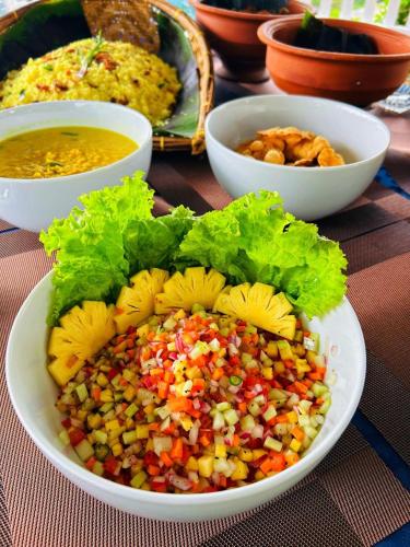 a plate of food on a table with bowls of food at Monticello Bungalow in Kotmale