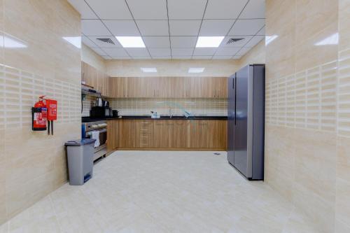a large kitchen with wooden cabinets and a stainless steel refrigerator at Sea-Facing 4BR Villa with Two Assistant Room, Heated Pool and Barbecue Space, Al Dana Island, Fujairah by Deluxe Holiday Homes in Fujairah