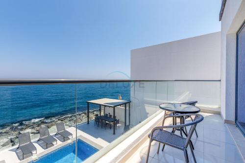 a balcony with a table and chairs and the ocean at Sea-Facing 4BR Villa with Two Assistant Room, Heated Pool and Barbecue Space, Al Dana Island, Fujairah by Deluxe Holiday Homes in Fujairah