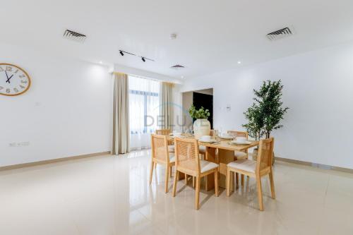 a dining room with a table and chairs and a clock at Sea-Facing 4BR Villa with Two Assistant Room, Heated Pool and Barbecue Space, Al Dana Island, Fujairah by Deluxe Holiday Homes in Fujairah