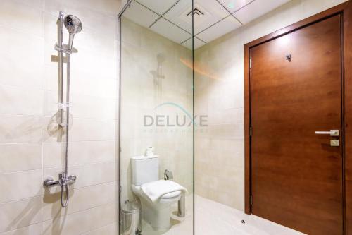 a bathroom with a toilet and a glass shower door at Sea-Facing 4BR Villa with Two Assistant Room, Heated Pool and Barbecue Space, Al Dana Island, Fujairah by Deluxe Holiday Homes in Fujairah