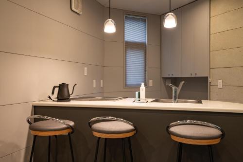 a kitchen with two stools at a counter with a sink at Izumigo Yatsugatake Dog Paradise Cottage in Hokuto