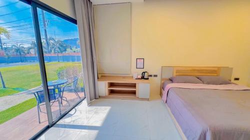 a bedroom with a bed and a table and a window at The Memories Hill Phuket in Thalang