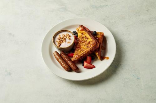 a plate of food with waffles and sausage and sauce at Holiday Inn Miami-Doral Area by IHG in Miami
