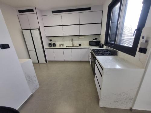 a kitchen with white cabinets and a stove top oven at chic boutique penthouse walk to the beach ashdod in Ashdod