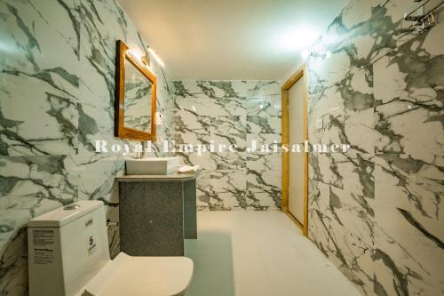 a bathroom with a toilet and a marble wall at Royal Empire Camp & Resort Jaisalmer in Sām