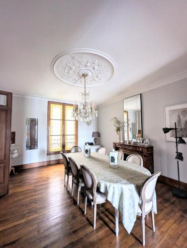 une salle à manger avec une table, des chaises et un lustre dans l'établissement Appartement 3 chambres vue sur la Garonne, à Bordeaux