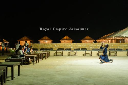 a group of people sitting at tables on a stage at Royal Empire Camp & Resort Jaisalmer in Sām