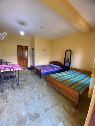 a room with two beds and a table in it at Relax mountain guest house in Badulla