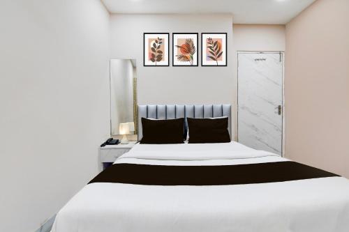 a white bedroom with a large white bed with black pillows at Super Hotel O Marquis Street formerly BK International in Kolkata