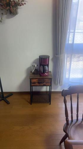 a room with a coffee maker on a table with a window at ペンションラモー in Karuizawa