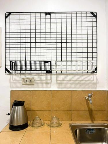 a kitchen counter with a sink and a metal tea kettle at BGC Suites EDSA Makati in Manila