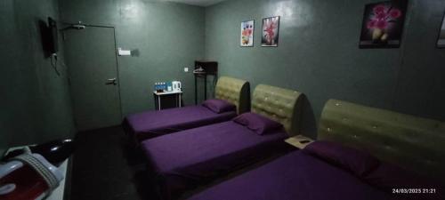 a room with two beds in a room with purple sheets at Hotel Oasis in Batang Kali