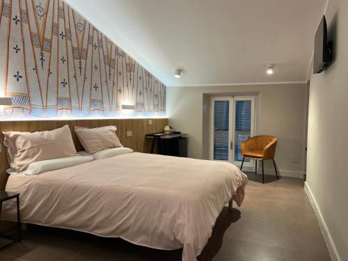 a bedroom with a large white bed and a chair at Antica Dimora Palazzo Ciprani in Anagni