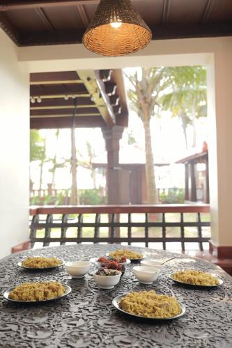 a table with many plates of food on it at Willo Stays Luxe Heritage Home , Udupi in Udupi