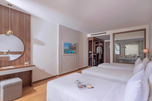 a white bedroom with a large white bed and a table at PANAMA Nha Trang Hotel in Nha Trang