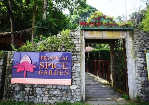 a sign for a tropical spice garden in a stone fence at La Ferringhi Villa - Tropical Collection, by ALV in Batu Ferringhi