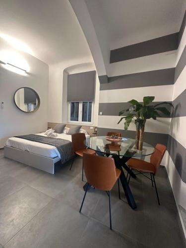 a bedroom with a bed and a glass table and chairs at Suite degli Archi - Genova Fronte Acquario in Genova