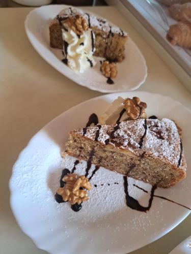 two plates of food on a table with a piece of cake at Albergo Miralaghi in Padergnone