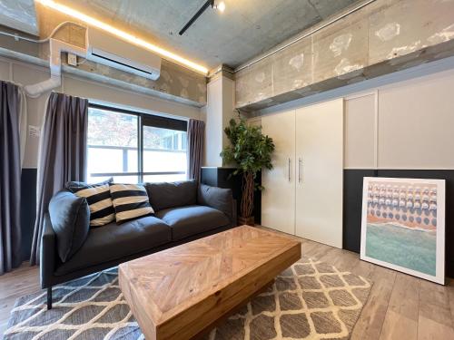 a living room with a black couch and a wooden coffee table at Eims stay Oomori206 in Tokyo
