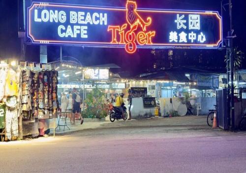 a long beach cafe sign on a street at night at La Ferringhi Villa - Balinese Collection, by ALV in Batu Ferringhi