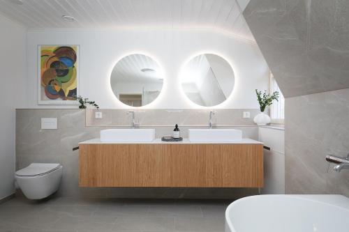 a bathroom with two sinks and two mirrors at Stay North - Marjaniemi in Salo