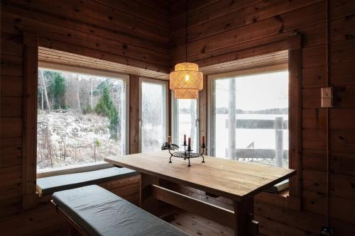 a dining room with a wooden table and two windows at Stay North - Marjaniemi in Salo
