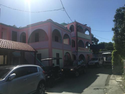 a pink building with cars parked in front of it at Mamacitas Guest House in Culebra
