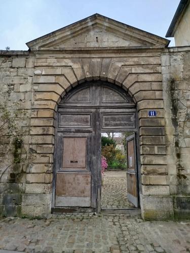 een oud stenen gebouw met een grote houten deur bij Irène in Senlis