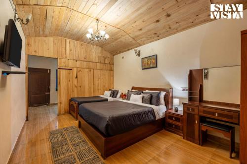 Un dormitorio con una cama, un escritorio y un televisor. en StayVista at Serenity of Sunny Side with TV, Lawn, Lake View, en Kodaikanal