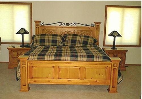 a bedroom with a wooden bed with a checkered blanket at ThunderHeart in Custer