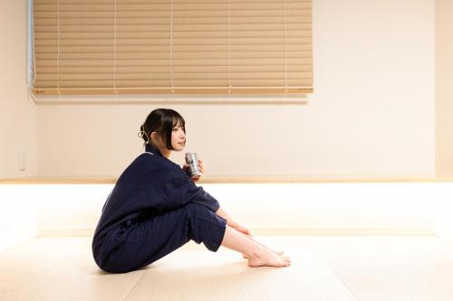 a woman sitting on the floor in a room at 乃宿-noyado-長崎 in Nagasaki