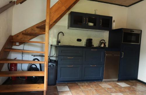 a kitchen with blue cabinets and a staircase in a room at Hostel Kersenhof in Uden