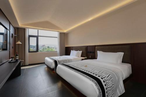 a hotel room with two beds and a window at Jinghong City Chenduo Nanshan Hotel in Xishuangbanna International Airport