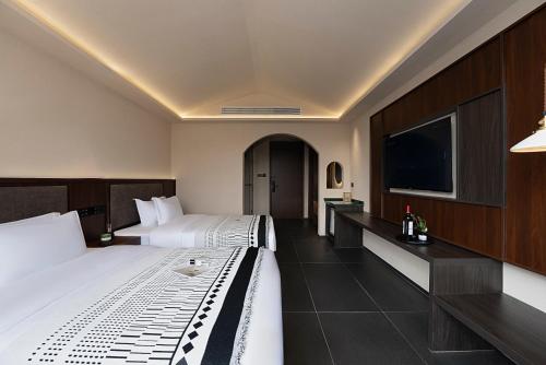 a hotel room with two beds and a flat screen tv at Jinghong City Chenduo Nanshan Hotel in Xishuangbanna International Airport