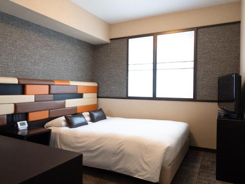 a bedroom with a bed and a large window at Hearton Hotel Kita Umeda in Osaka