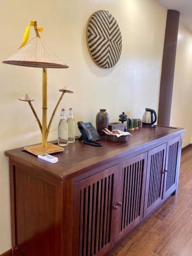 a wooden cabinet with a lamp on top of it at Hồ Đá Cổ Thiên Long Resort Hòa Bình in Hòa Bình